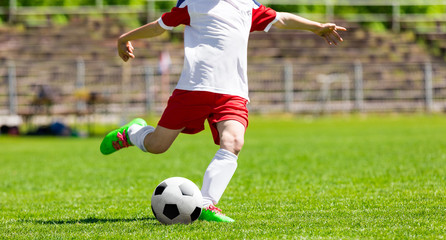 Youth Football Soccer Player Hits a Ball. Footballer Kicking Ball on Grass Pitch