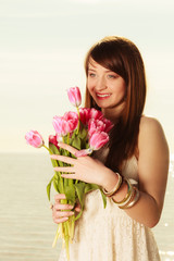 Portrait of woman holding pink flowers on beach