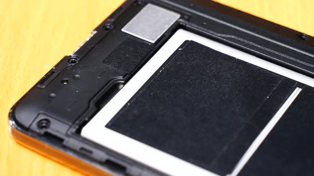 Male human hand putting battery into phone. Smartphone fixing, technology repairing concept.