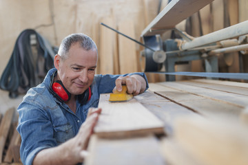 Image of male joinery worker smoothening piece of wood