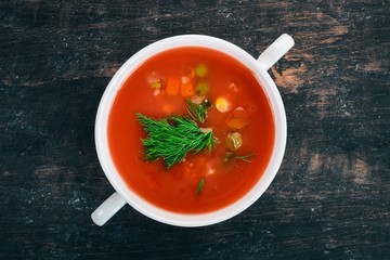 Tomato soup with chili and vegetables. Healthy food. On a black wooden background. Top view. Copy space for your text.