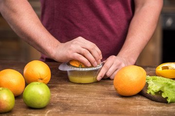 cropped shot of young man squeezing fresh orange juice at home