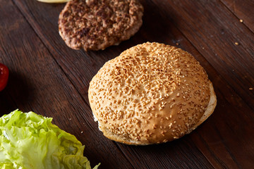 Yummy hamburger ingredients artistically organized on wooden plate, close-up, top view, selective...