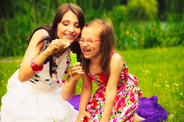 Obraz premium Mother and child blowing soap bubbles outdoor.