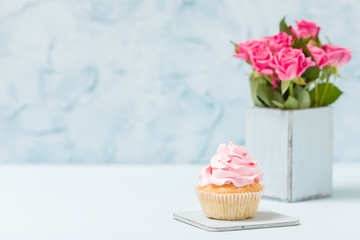 Cupcake with pink decoration and bouquet of roses in blue retro shabby chic vase.