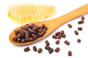 Granules of bee bread in a wooden spoon and a honeycomb are isolated on a white background. Apitherapy. Beekeeping products. Strengthening immunity.