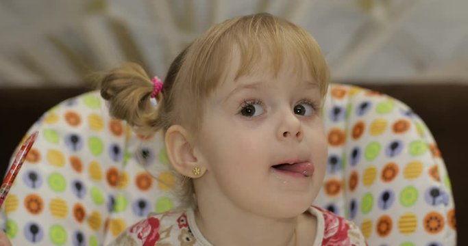 Beautiful two years old girl shows her tongue. Thumbs up. Ok. Cute blonde child. Brown eyes. Close up