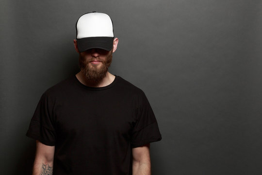 Hipster man walking wearing black jeans, t-shirt and a white baseball cap