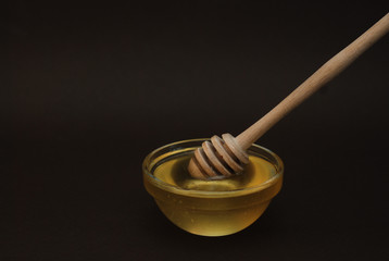 Honey in Glass bowl with dipper over dark Background Isolated with copy space.