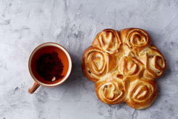 Homemade rose bread, cup of tea, dried citrus and spicies on white textured background, close-up, shallow depth of field