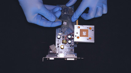 Master in blue rubber gloves, repairing the board, chip, cleaning the video card, soldering a spot,...