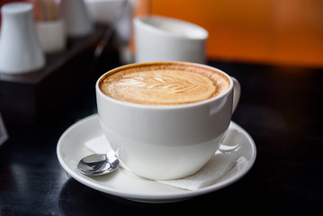 Cappuccino in a white cup on restaurant table