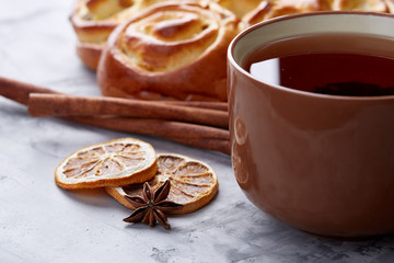 Homemade rose bread, cup of tea, dried citrus and spicies on white textured background, close-up, shallow depth of field