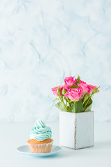 Blue pastel vertical banner with decorated cupcake and bouquet of pink roses in retro shabby chic vase.