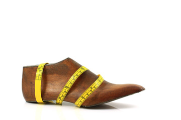 Wooden last shoe with measuring tape on white background