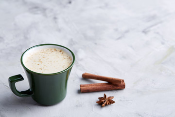Cup of creamy coffee with cinnamon and star anise on a white textured background, top view, close-up, selective focus