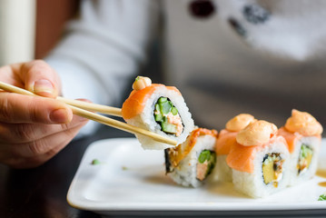 Young woman eats sushi rolls with chopsticks