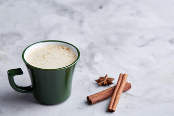 Cup of creamy coffee with cinnamon and star anise on a white textured background, top view, close-up, selective focus