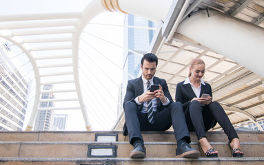 Two businesspeople looking on phone with happily and funny, relax and lifestyle in freetime.