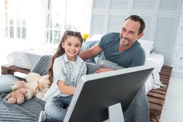 Leisure time. Delighted positive nice father and daughter smiling and having fun together while resting at home