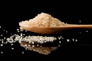 Brown sugar in wood spoon on black background.Components of The food is sweet delicious.