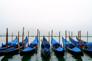 Venice gondolas parked at San Marco square, a foggy morning with gray sky