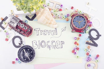 TRAVEL BLOGGER word written on yellow paper and decorative items