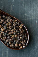 Close up black peppercorn in spoon dark background