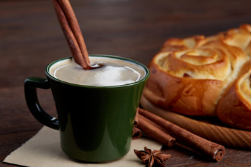 Creamy coffee in cup with homemade rose bread on vintage wooden background, close-up, selective focus