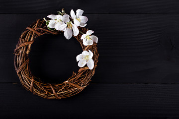 Wreath with spring flowers on a dark wooden background.