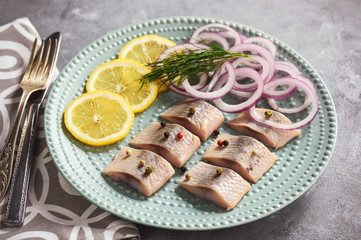 Pickled herring with red onion and lemon slices.