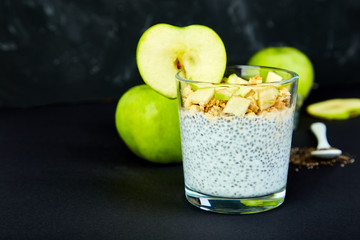 Healthy chia pudding with apples and granola in glass.