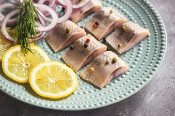 Pickled herring with red onion and lemon slices.