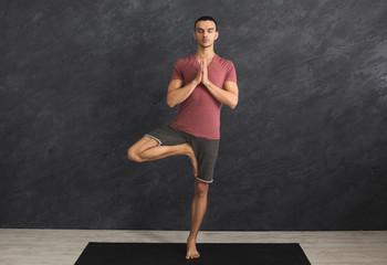 Young man training yoga in tree pose