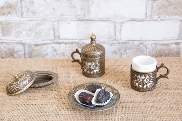 Turkish coffee with dried dates, brick wall background.