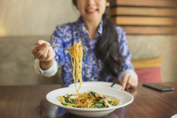 Spaghetti on a fork. Girl keeping fork with spaghetti. Spaghetti with sauce and Basil in wooden background.