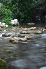 Naklejka na ściany i meble The river flows between the stones in summer
