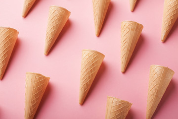 Waffle ice-cream cones on pink surface
