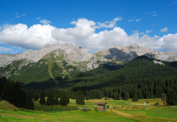Fototapeta na wymiar Golf course with wood and dolomites as a backdrop - Madonna di Campiglio - Trentino Alto Adige