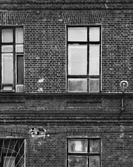 Fragment elewacji starego ceglanego budynku. Wysokie okna i materiały teksturowane. Czarno-biała stylizacja. - 197039399