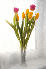 A bouquet  tulips in a vase on the windowsill