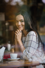 Beautiful young brunette sitting in a cafe and drinking tea.