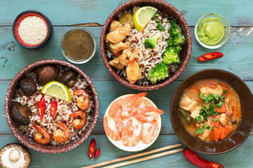 Rice with prawns, chicken, mushrooms, broccoli on a naked rustic background. Asian dishes. Concept of Asian food. View from above.