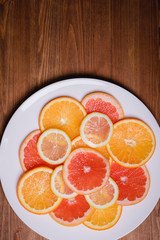 orange grapefruit and lemon cutting into a plate on a wooden background