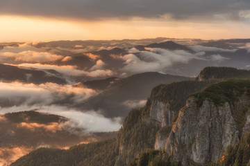 Fototapeta premium Beautiful mountain view with fog over the peaks at sunrise, Ceahlau massif, Eastern Carpathians, Moldova, Romania