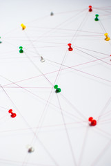 Background. Abstract concept (idea) of network, social media, internet, teamwork,  communication abstract. Colorful push pins linked together by red thread. Isolated. Entities connected.
