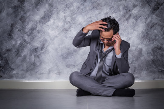 depressed businessman with mobile phone and sitting on the floor