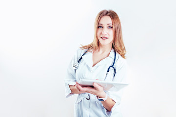Fototapeta premium doctor in white medical coat is using a tablet and smiling while standing against window