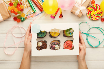 Assortment of tasty cupcakes with colorful buttercream tops in female hands