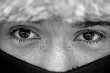 A teenager in a fur hat and a face covered with a scarf on a cold winter day